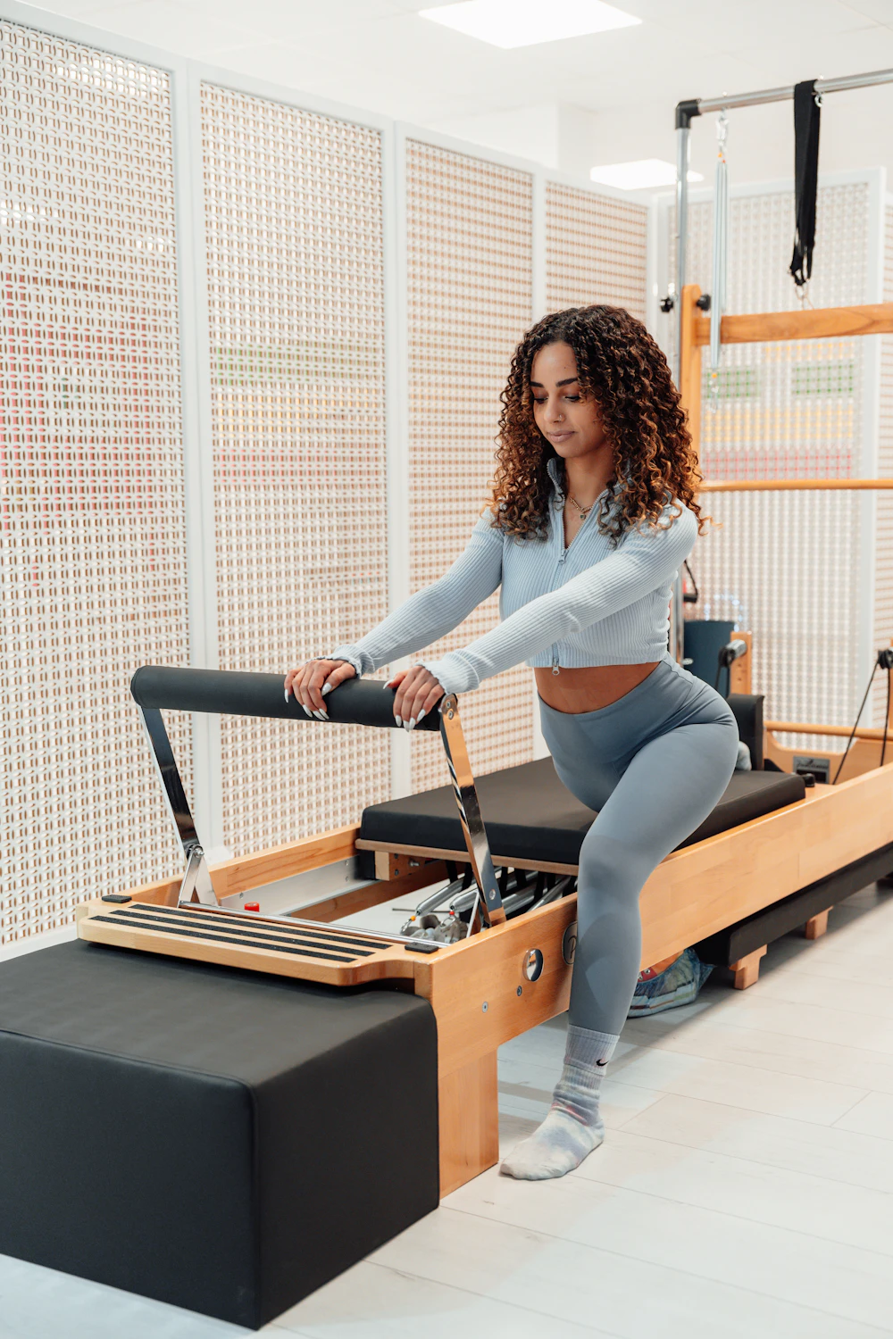 A woman training on a reformer with her feet on the footplate