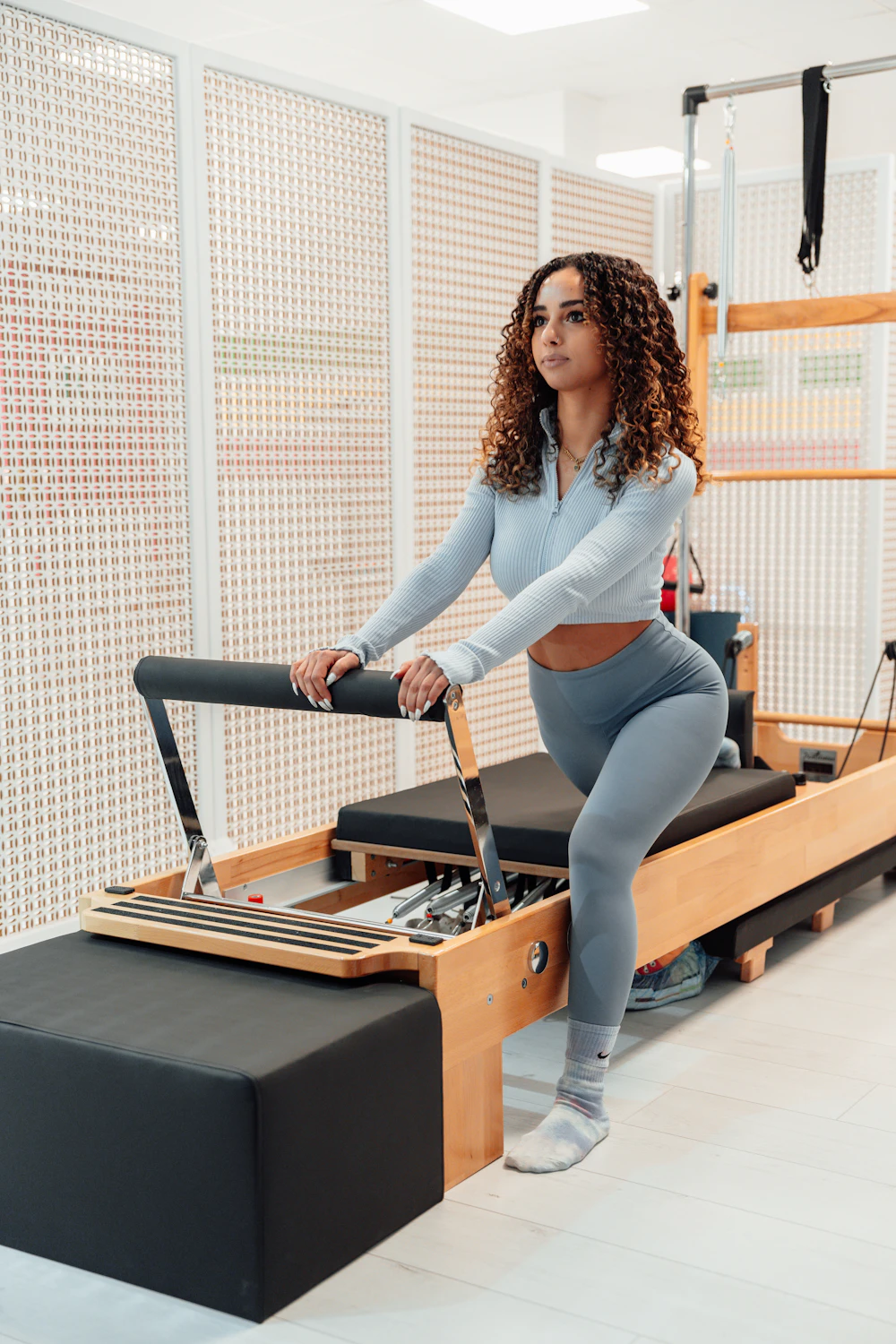 A woman pushing the carriage of a reformer with her legs