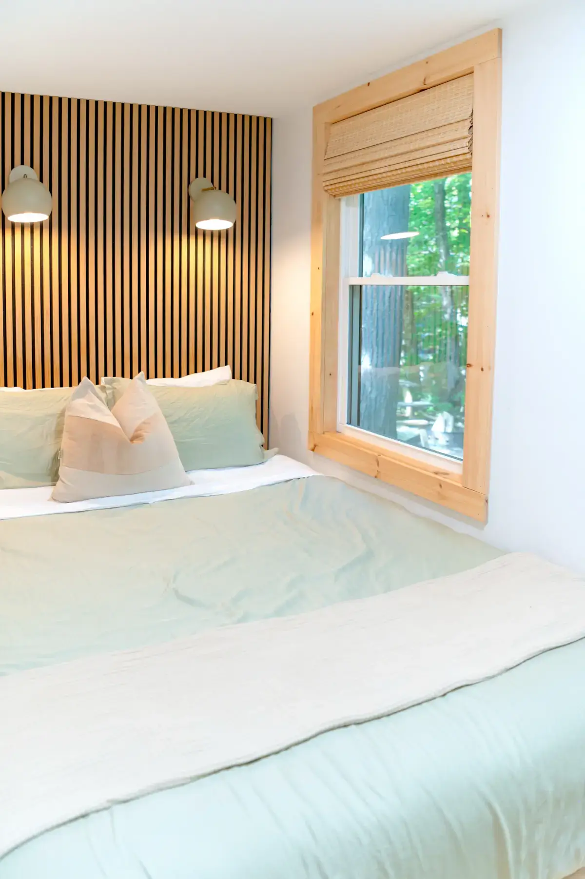The Hav bed with sage bedding against a slatted wooden wall
