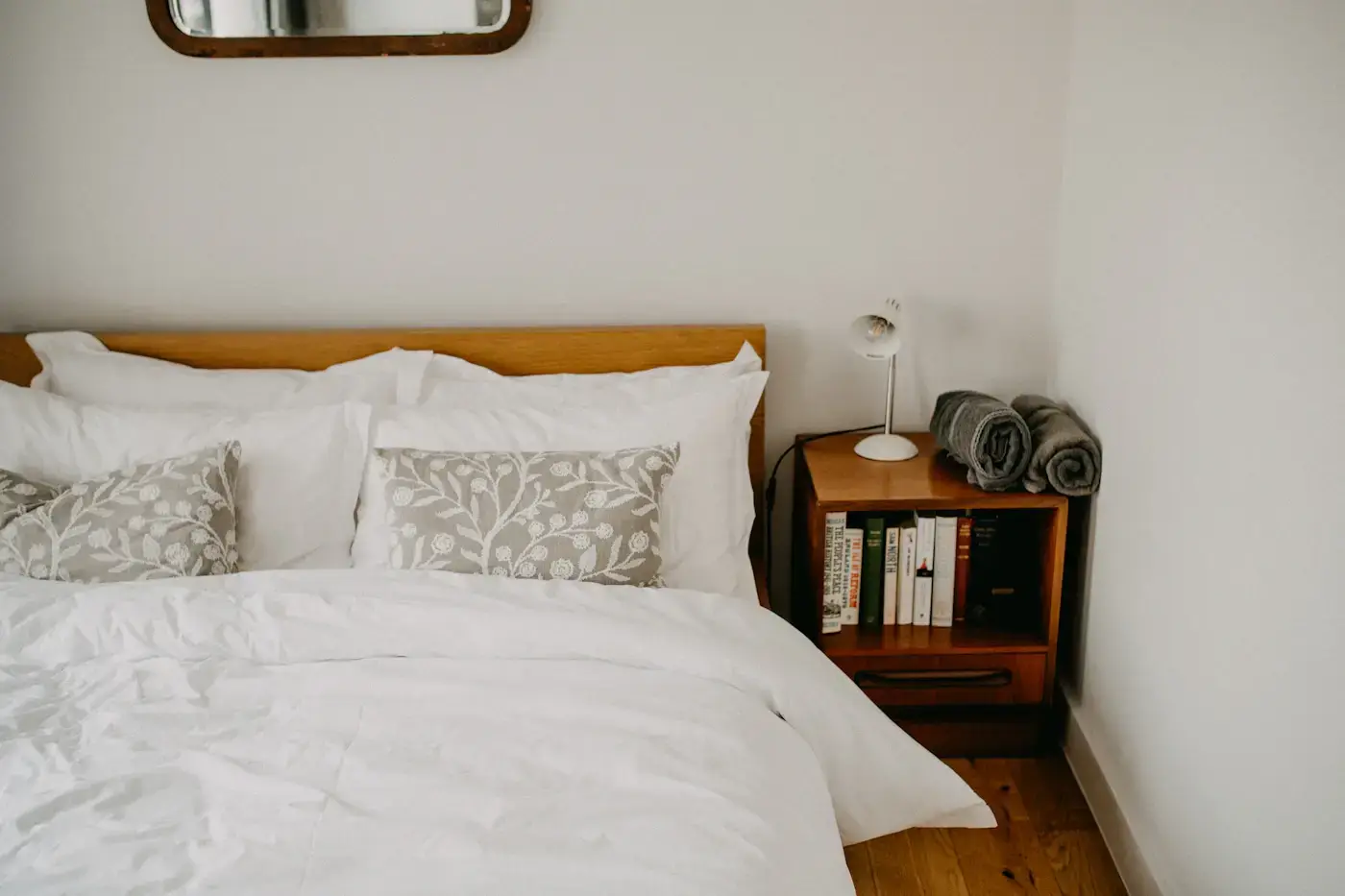 A calm bedroom with a neatly made bed and a wooden bedside table
