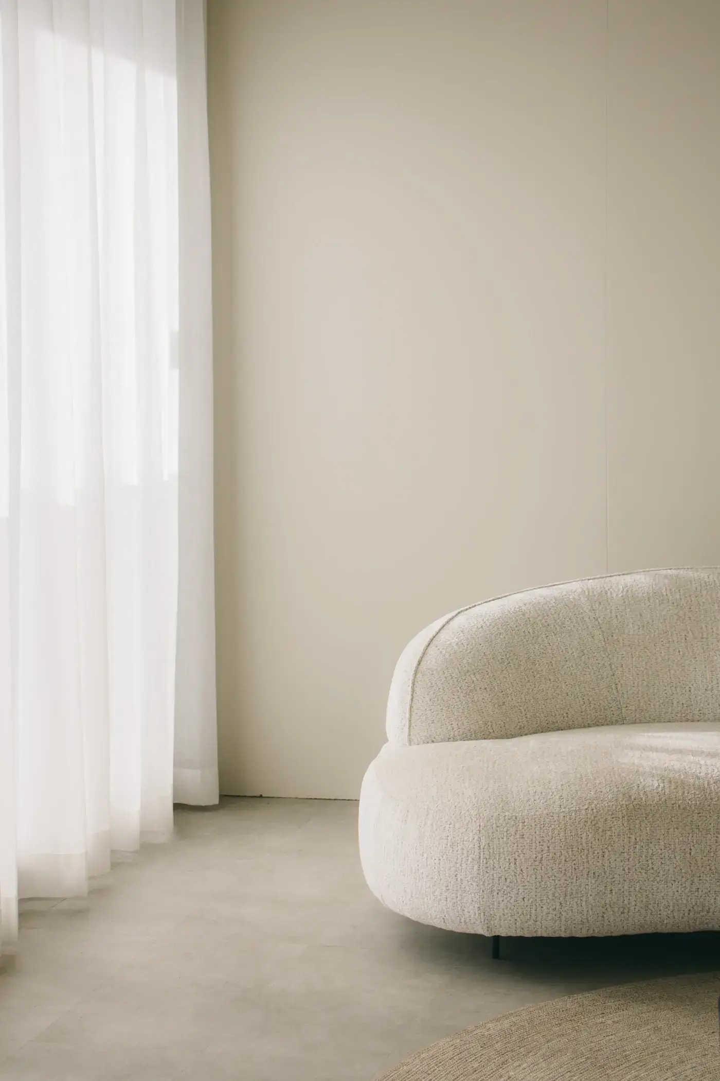 A white sofa beside a tall window in a quiet Scandinavian living room