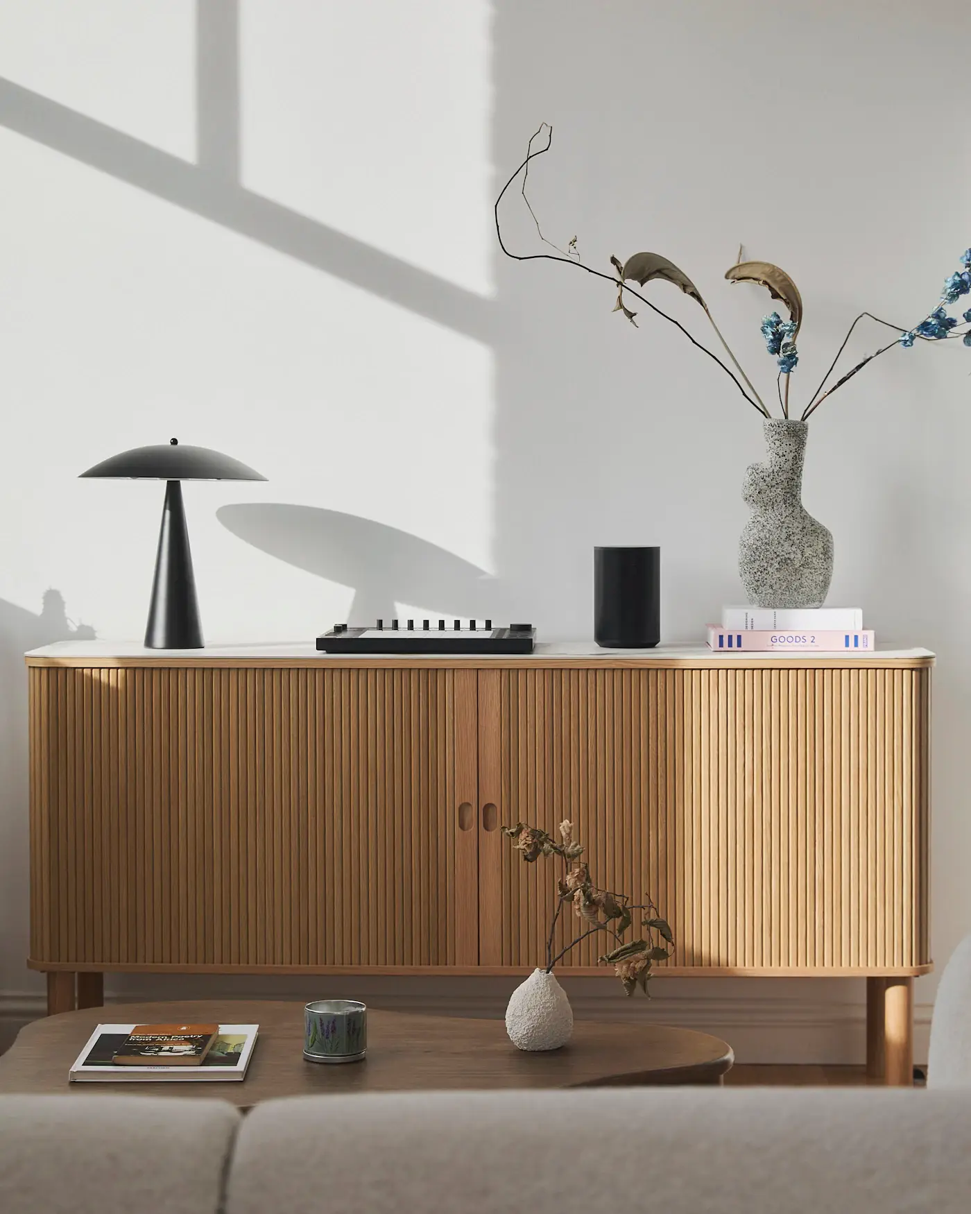 A low wooden sideboard with a lamp and ceramics against a pale wall
