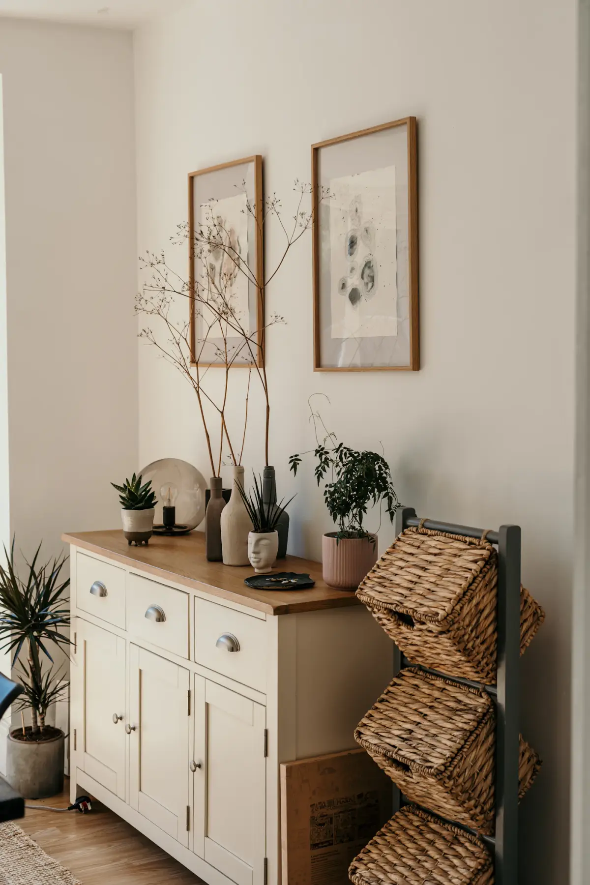 The Tind oak sideboard styled with plants, vases and wicker baskets in a living room