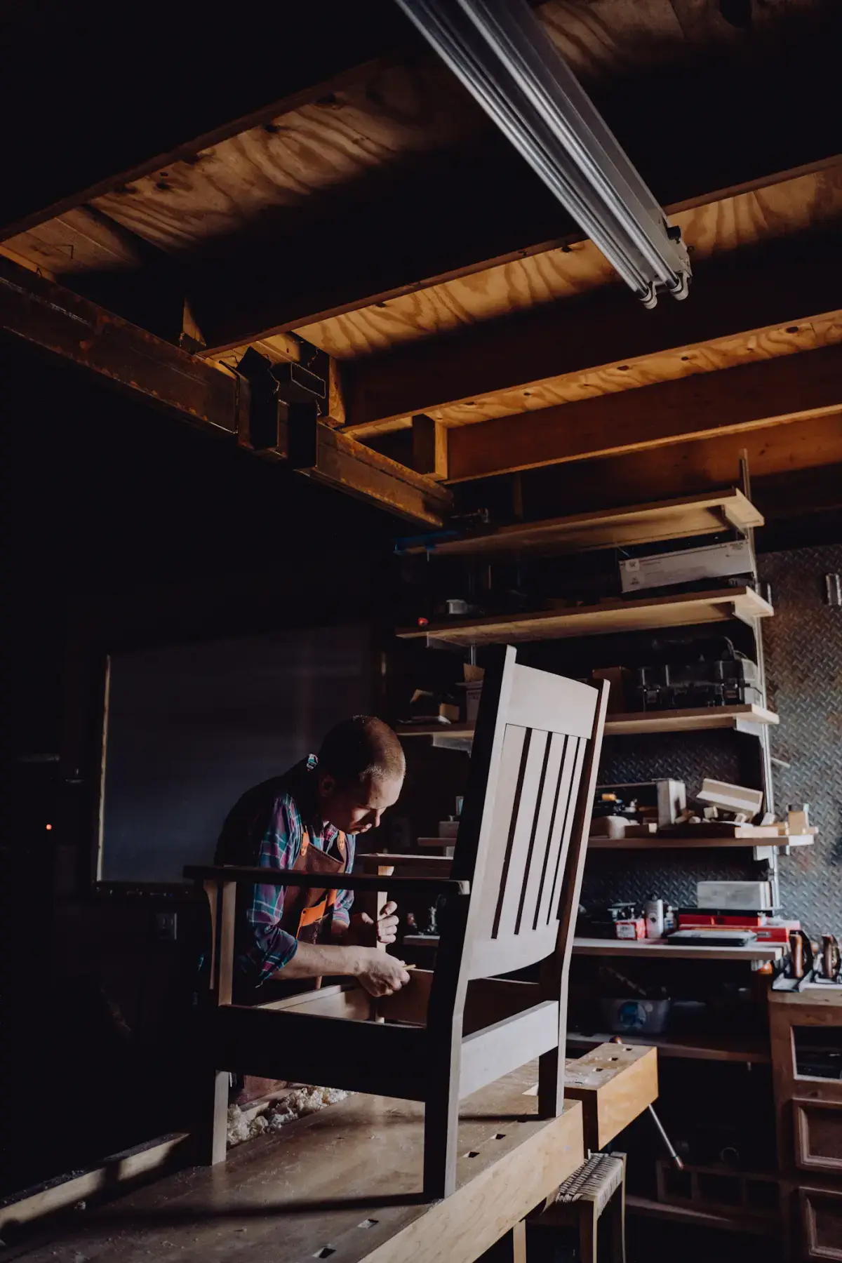 A furniture maker fitting the frame of a wooden chair in the workshop