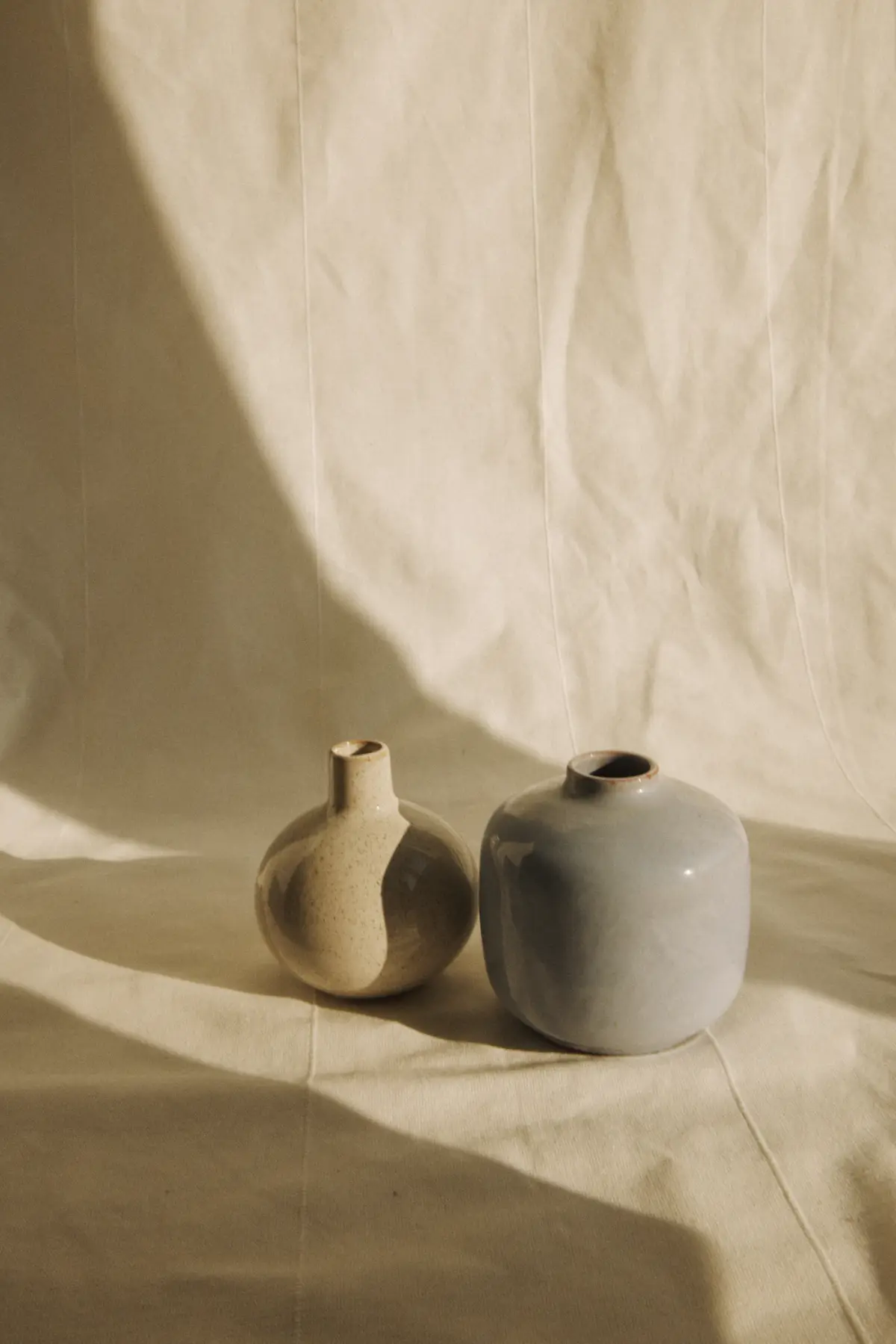 Two small stoneware vases in sand and grey glazes in soft afternoon light