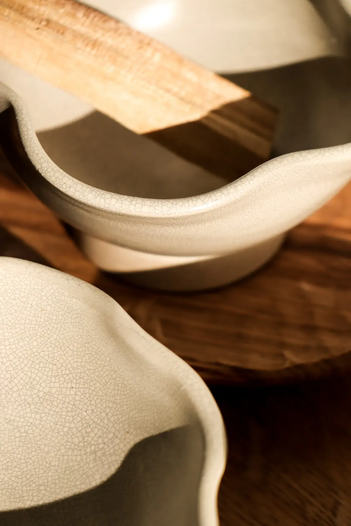 Close-up of the cream Slip serving bowl with its wavy rim on a wooden table
