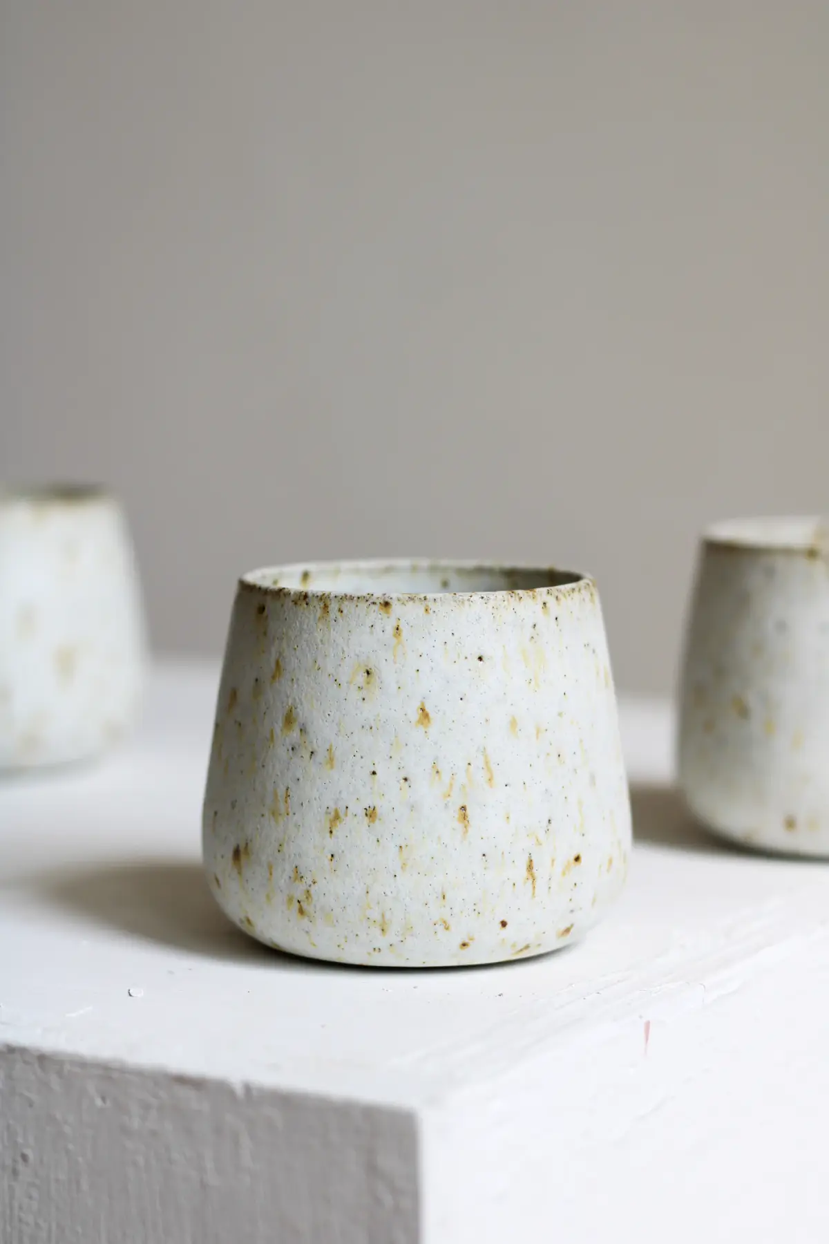 A speckled white stoneware tumbler on a white table