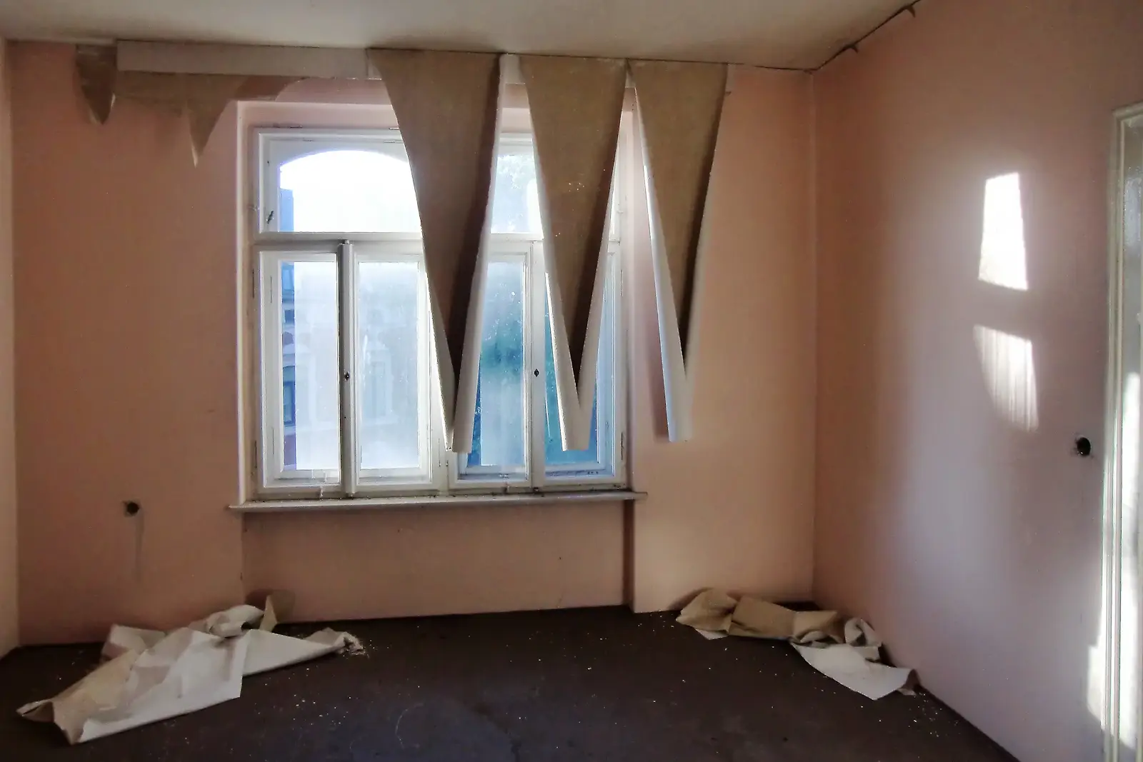 Before: an empty room with peeling wallpaper, bare floorboards and a tall window