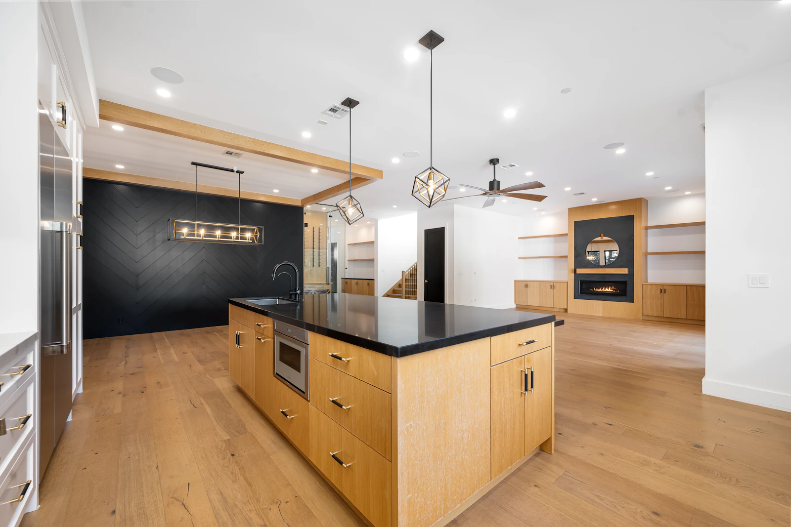 After: an open kitchen with a large oak island, black worktops and pendant lights