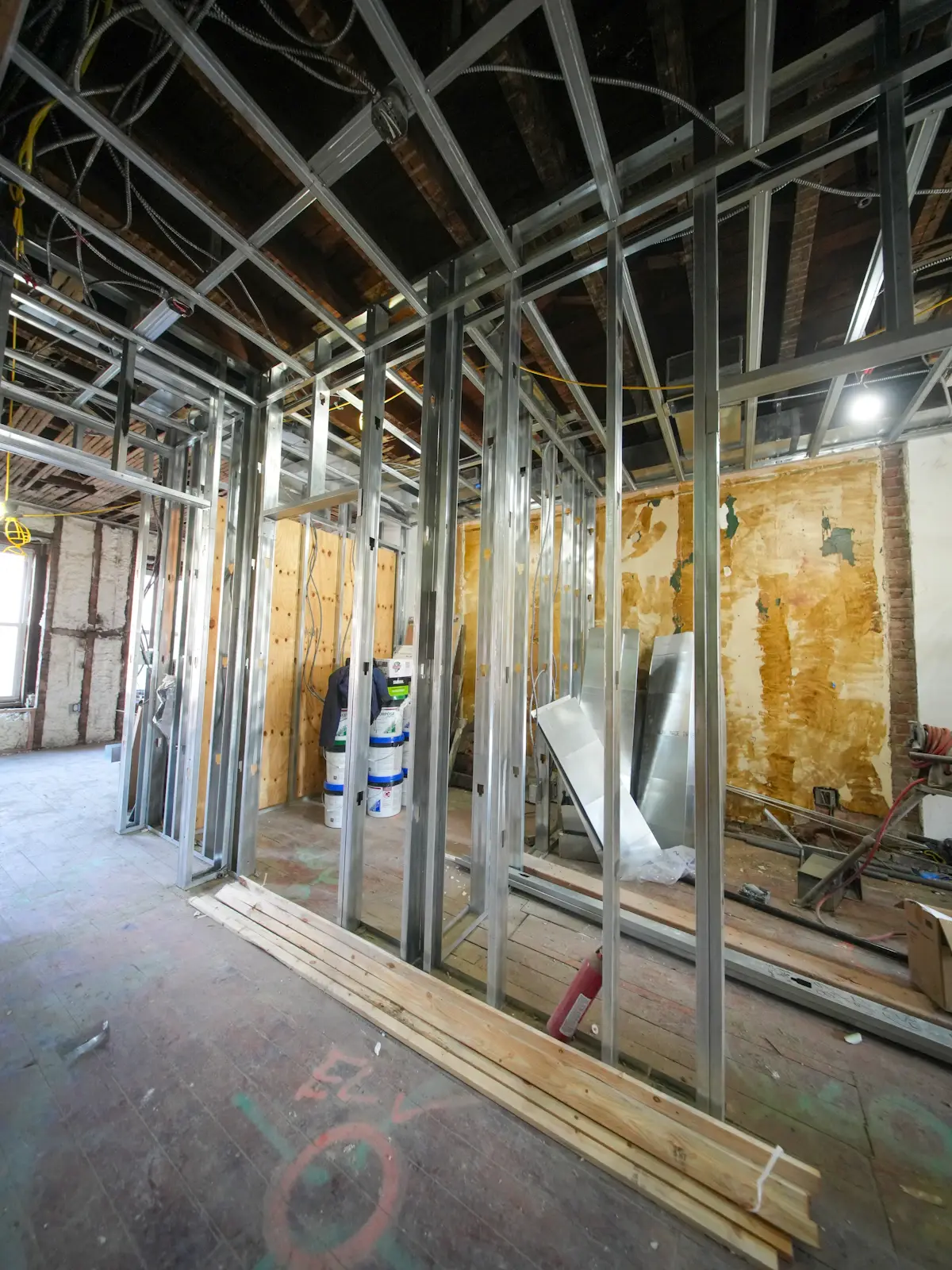A renovation site with new metal stud walls and exposed old plaster