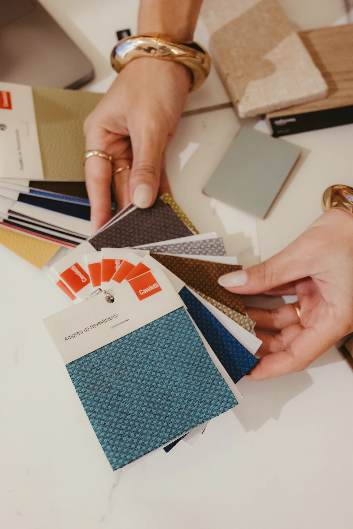Hands choosing between fabric and colour samples from a designer's palette