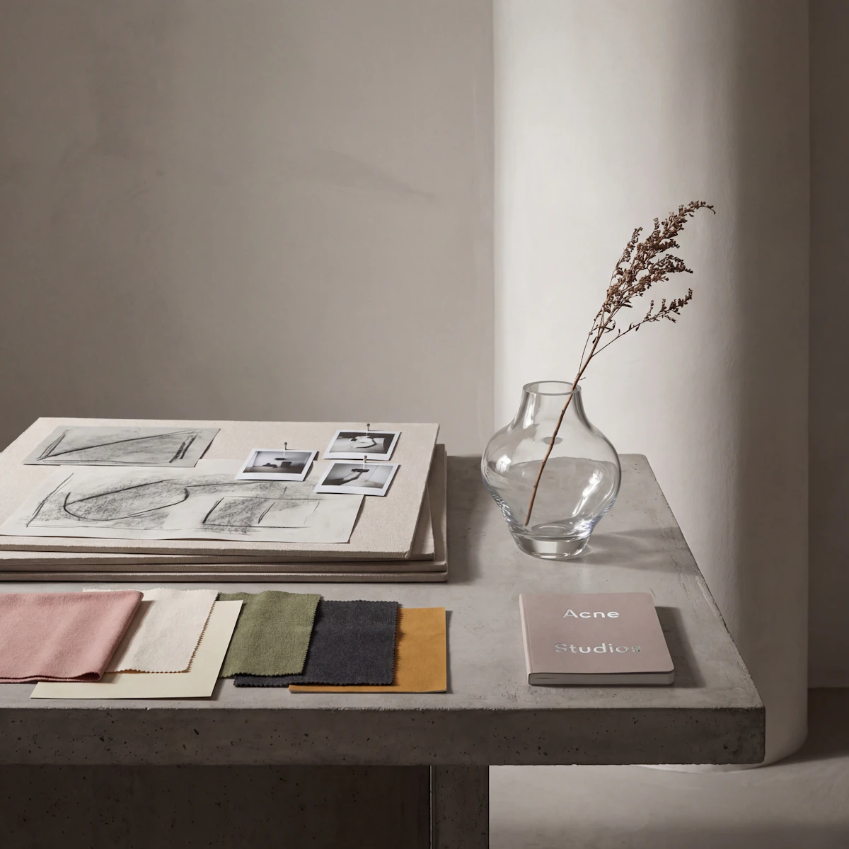 Fabric swatches, sketches and a vase laid out on a studio table