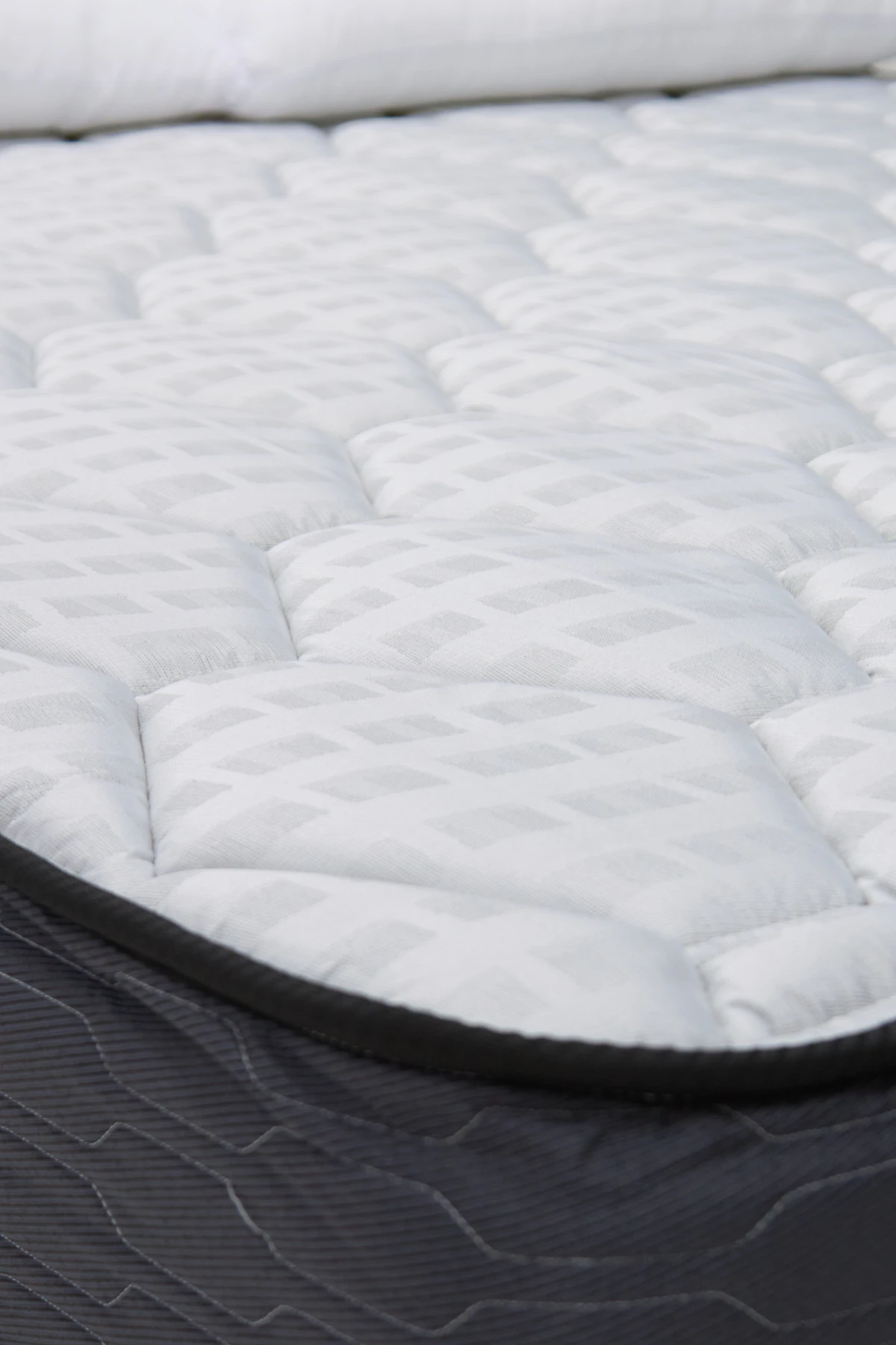 Close-up of a white quilted mattress topper with soft stitched panels