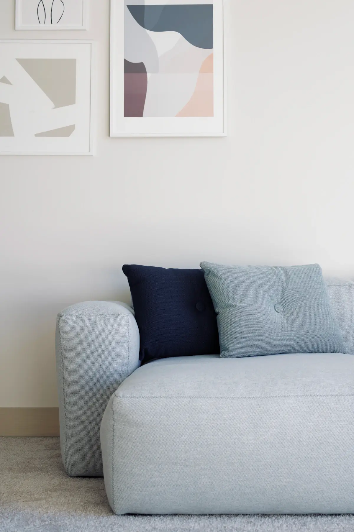 The Mellow sofa in chalk fabric with navy and pale blue cushions against a white wall