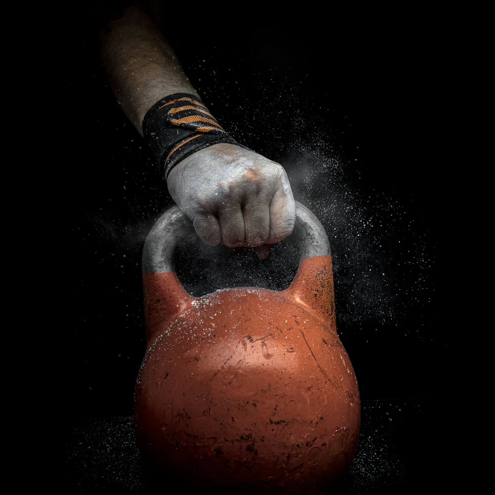 A hand covered in chalk gripping a kettlebell