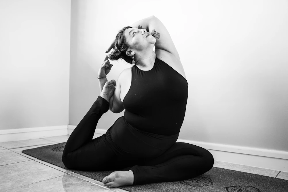 A pregnant woman in a supported seated yoga pose, in black and white