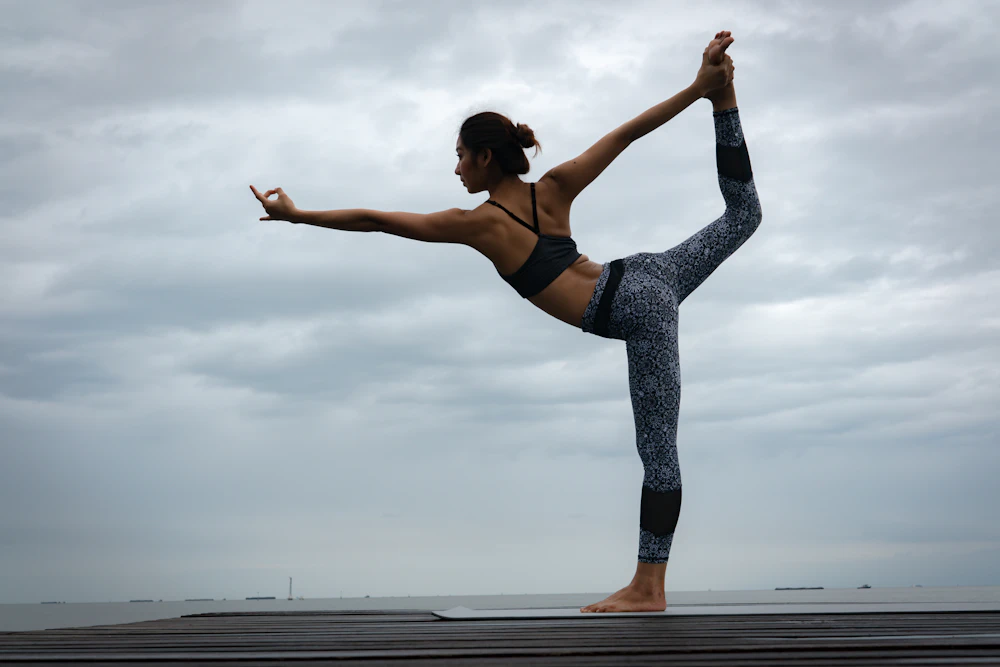 A woman holding a balancing yoga pose in soft grey mist