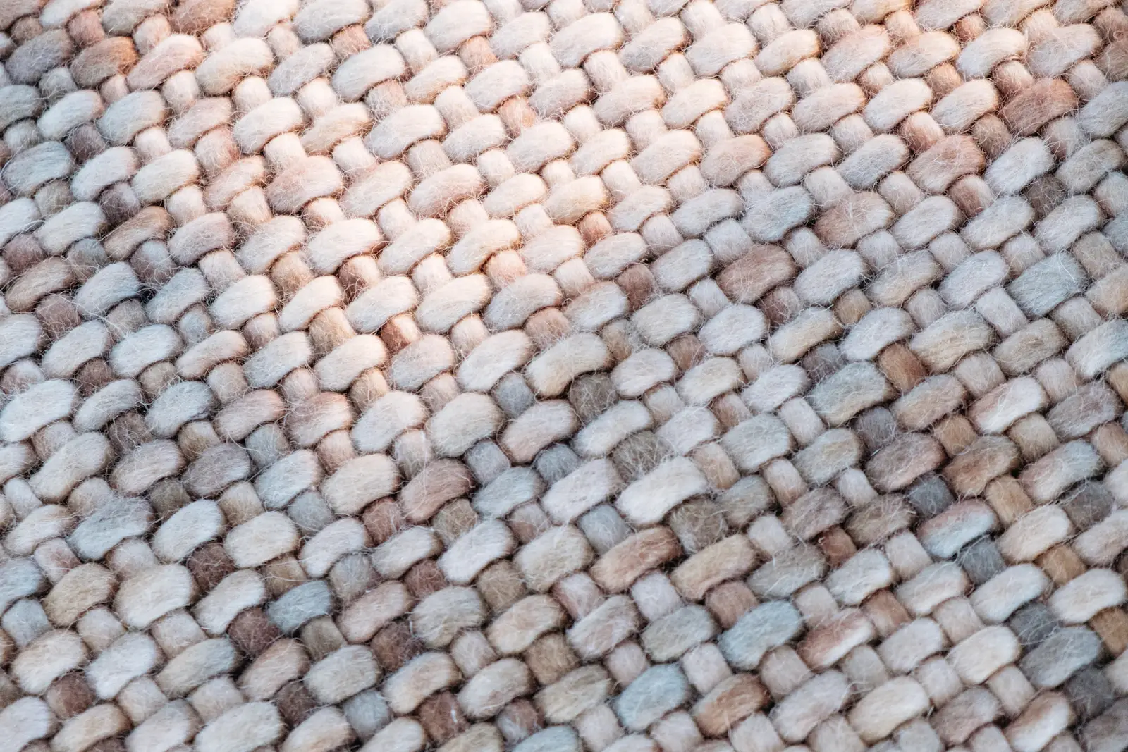 Close-up of the Dune rug: chunky braided wool in cream, grey and soft pink