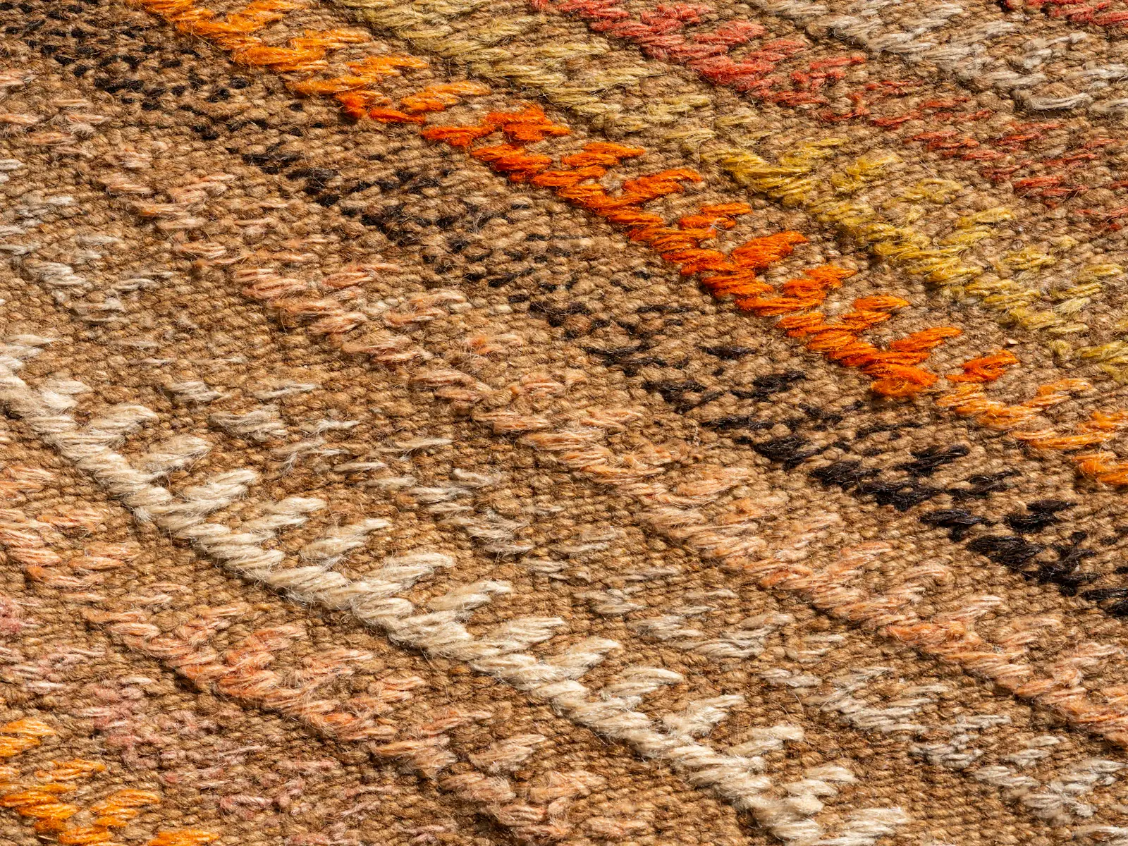 Close-up of the Ember kilim weave in bands of rust, orange, sand and cream